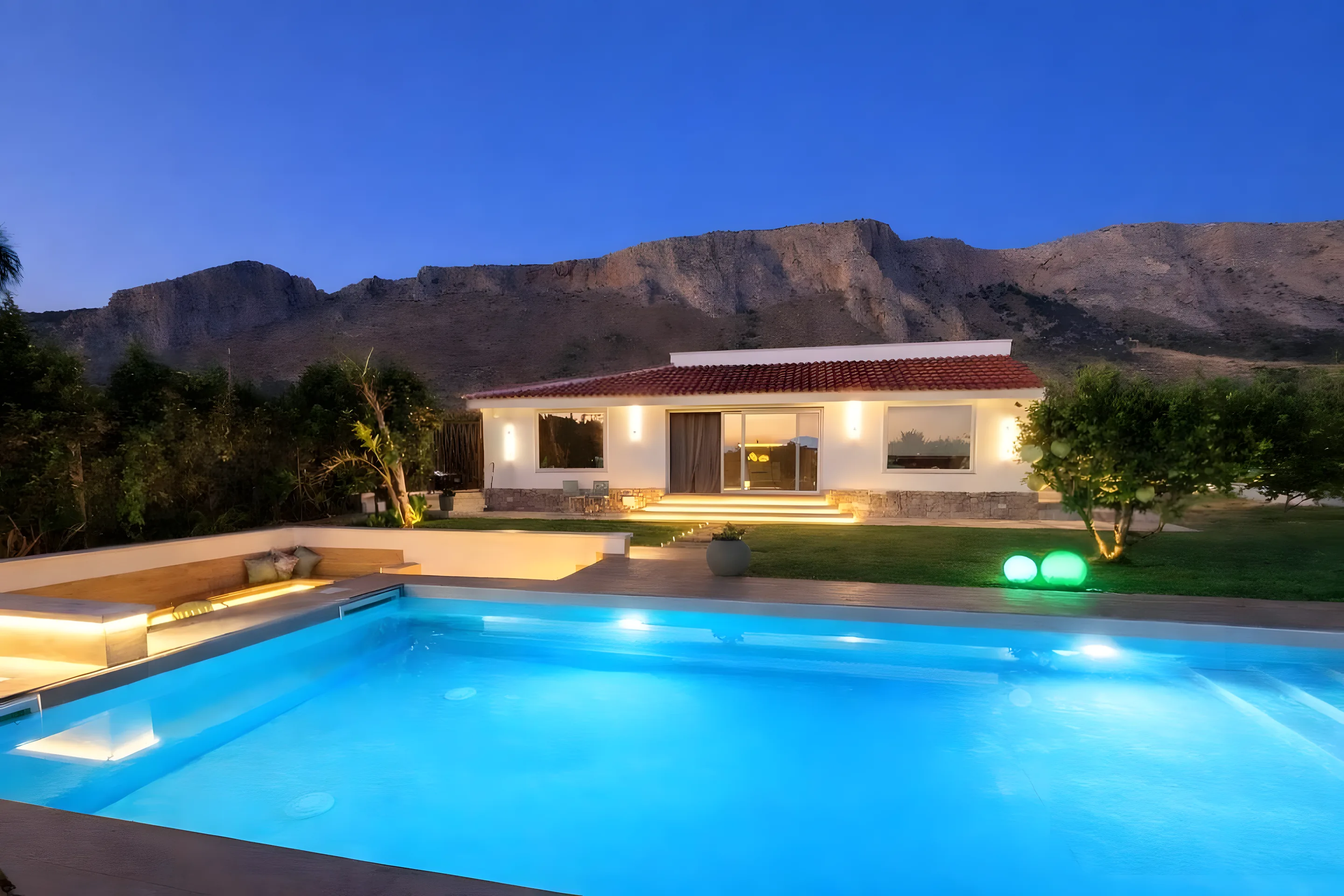 Villa ScrusciuHoliday con piscina illuminata e montagne al crepuscolo