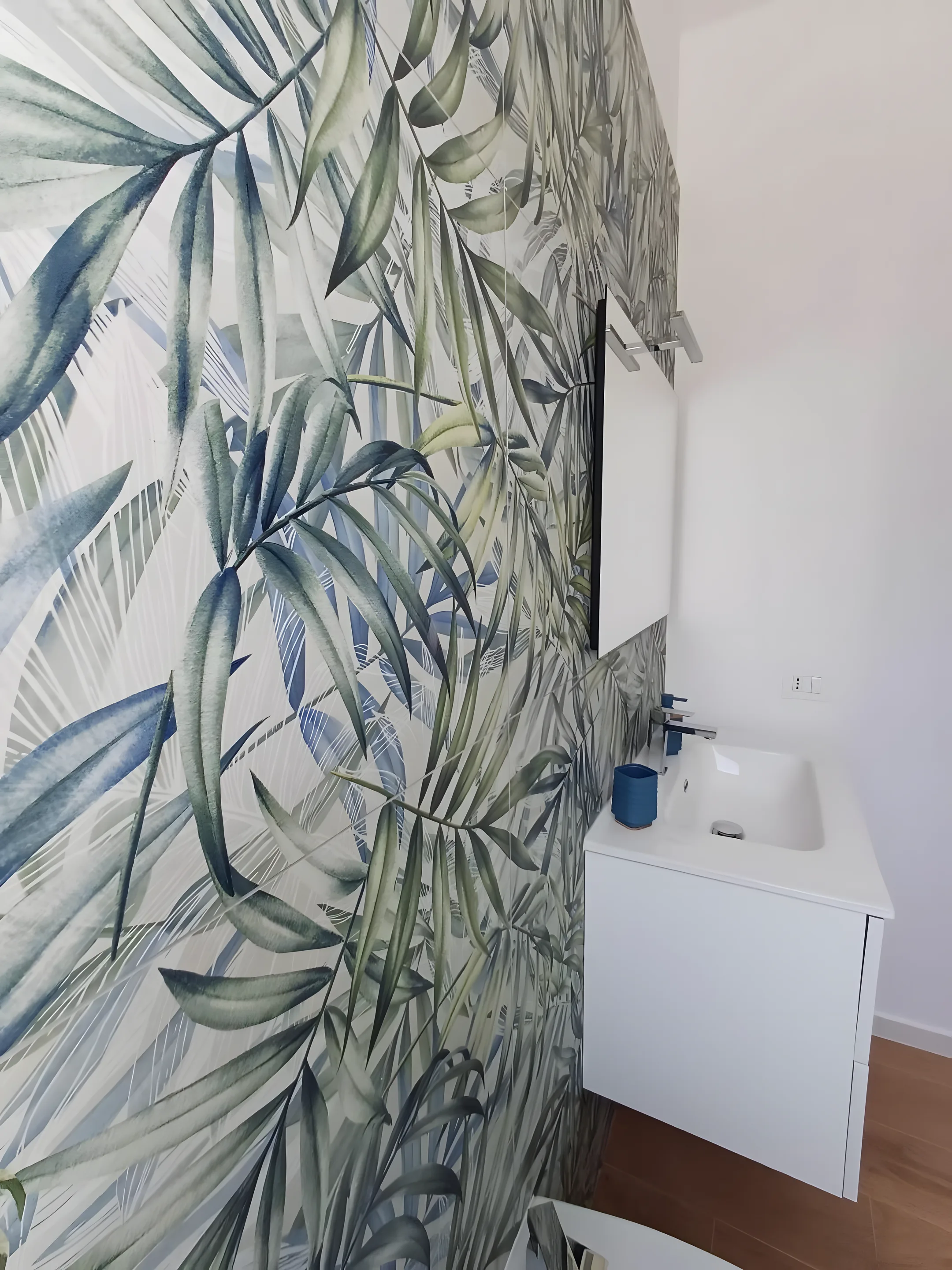 Bagno con carta da parati tropicale e lavabo bianco