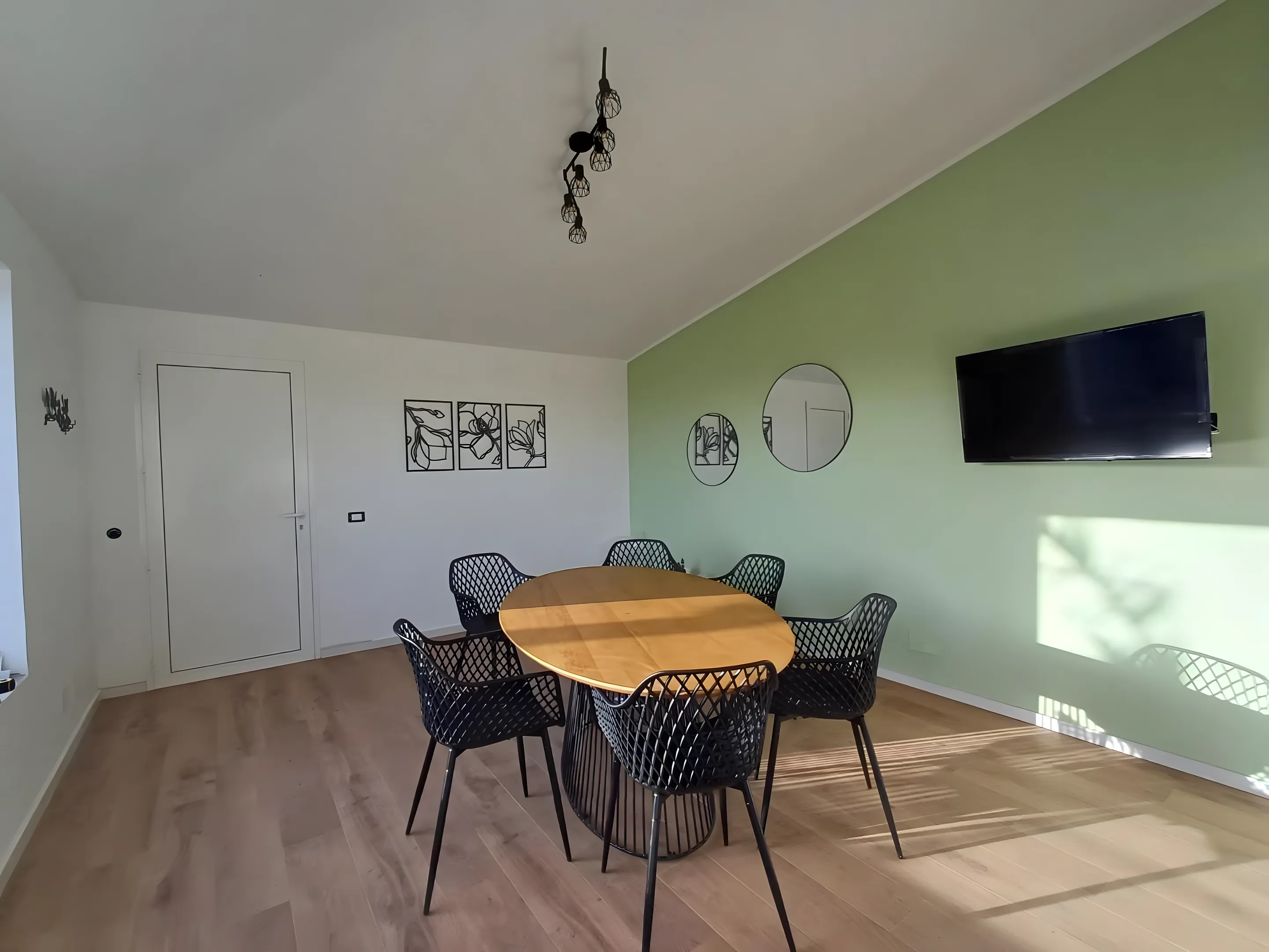 Sala da pranzo con tavolo rotondo e parete verde salvia