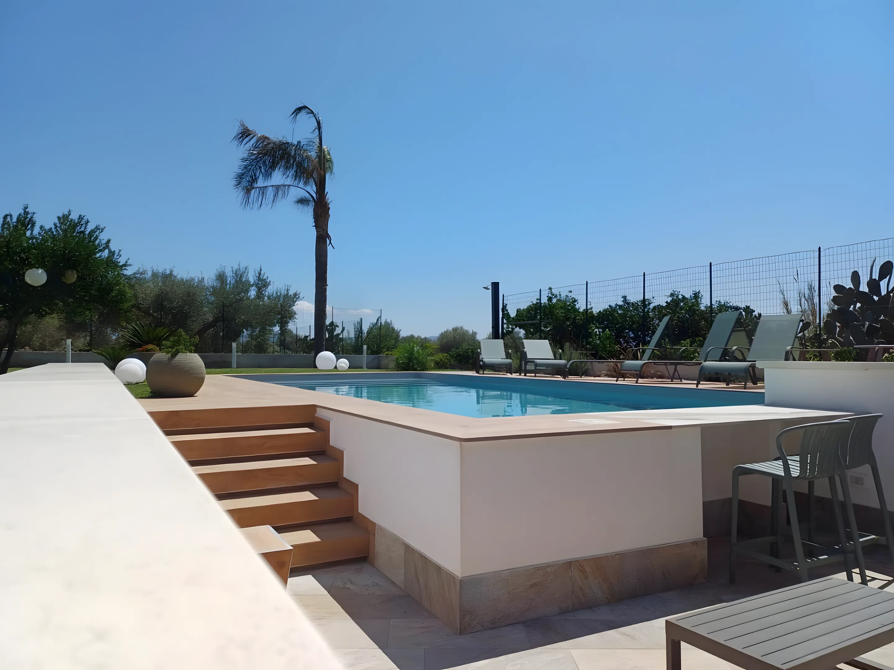 Piscina rialzata con scala in legno e palma