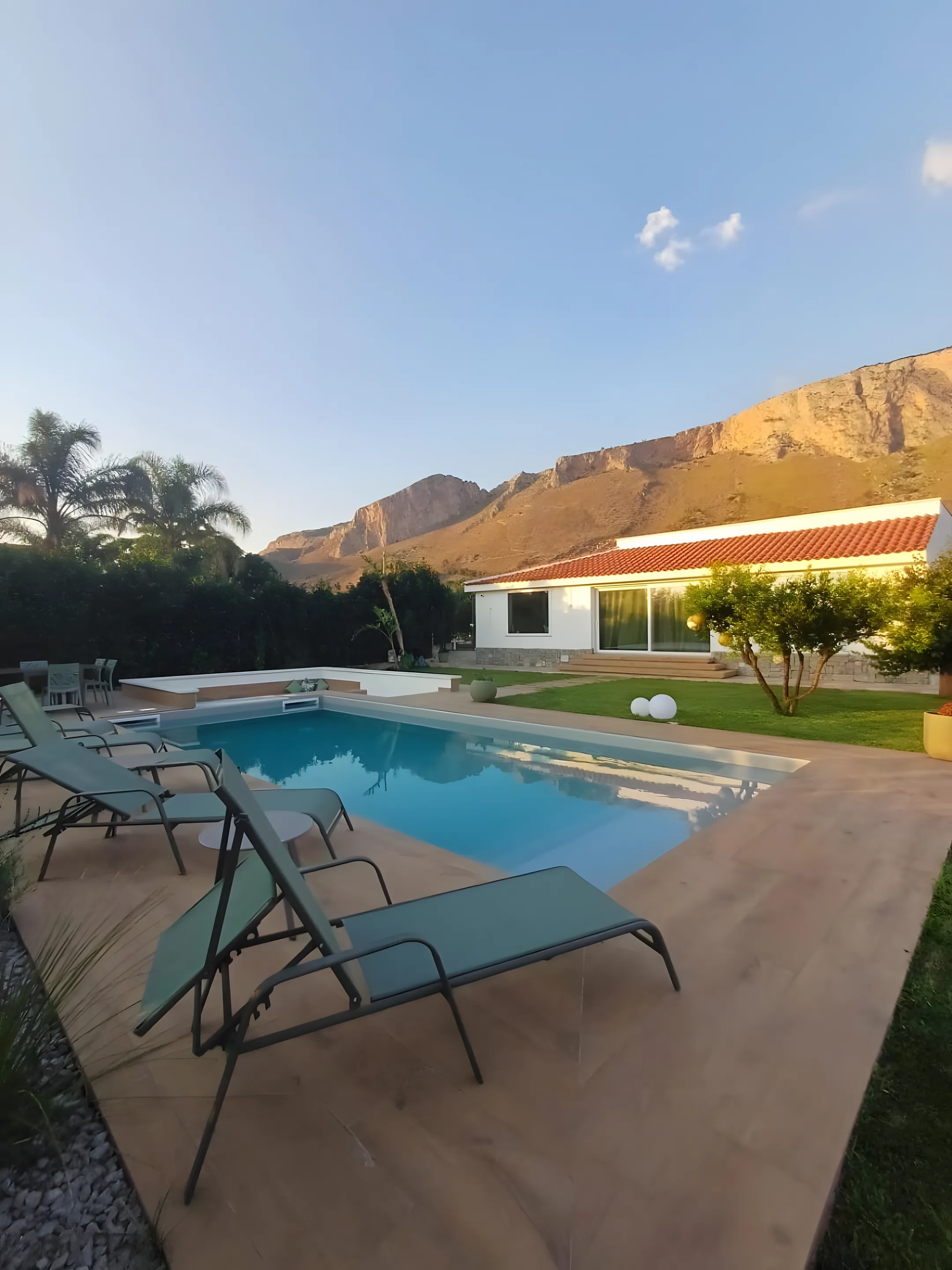 Villa con piscina e lettini ai piedi della montagna