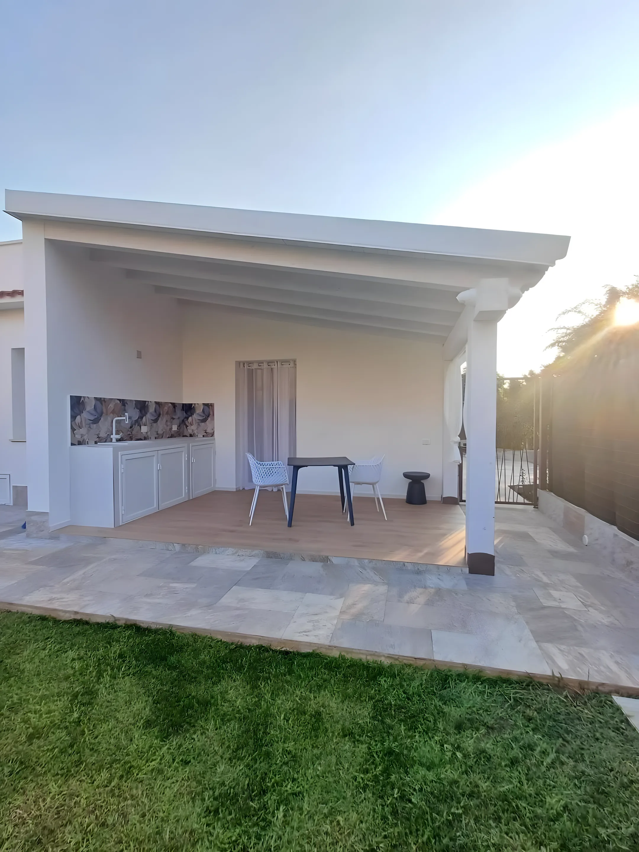 Portico della dépendance con tavolo e vista sul giardino al tramonto